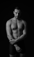 Fototapeta na wymiar Portrait of muscular young bodybuilder on dark background, black and white effect