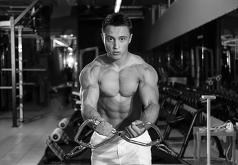 Fototapeta na wymiar Muscular young bodybuilder training in gym, black and white effect