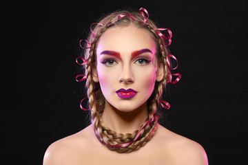 Young woman with dyed eyebrows on black background