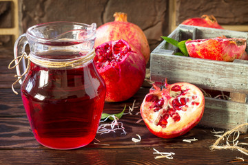 Freshly squeezed pomegranate fruit juice and ripe pomegranate on a wooden table. The concept of nutrition for superfoods and health or detoxification.