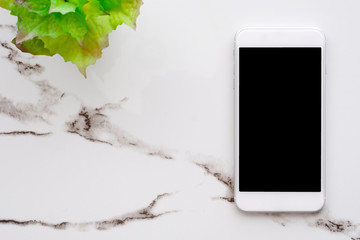 White smart phone with blank screen on white marble table background for mock up, template, technology and lifestyle concept