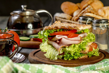 Sandwich with ham, cucumber, tomato and lettuce.