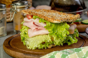 Sandwich with ham, cucumber, tomato and lettuce.