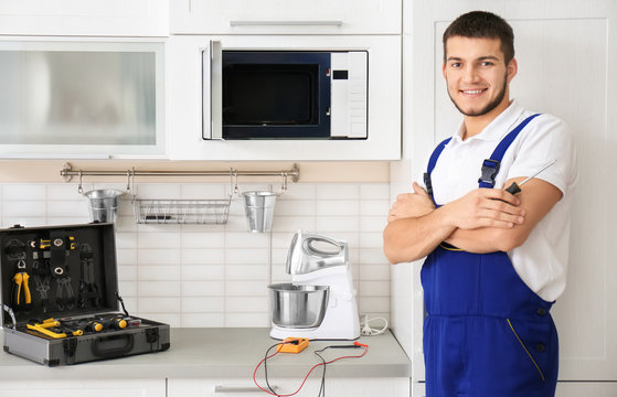 Young worker standing near microwave oven in kitchen