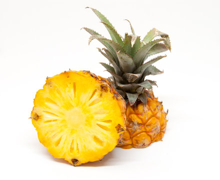 ripe tasty baby pineapple cut in half over white background