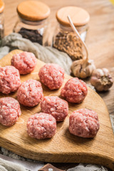 Raw meatballs on the wooden cutting board.