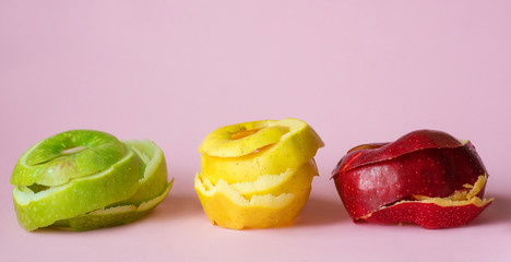 red, green, yellow apple peels on pink background as a symbol of recycling circulate economy