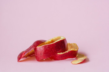 Red apple peel on pink background as a symbol of recycling circulate economy
