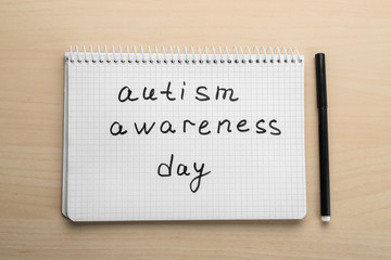 Notebook with phrase "Autism awareness day" on light background