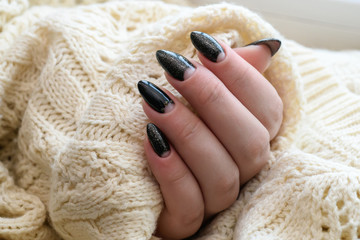 Beautiful winter manicure. Black lacquer with luster and white patterns of snow and frost. The white background is also with beautiful curled drawings