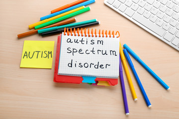 Notebook with phrase "Autism spectrum disorder" on table