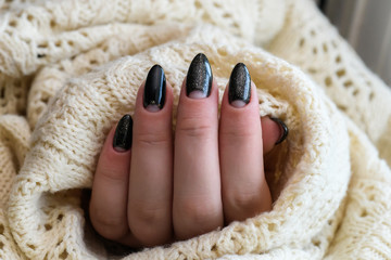 Beautiful winter manicure. Black lacquer with luster and white patterns of snow and frost. The white background is also with beautiful curled drawings