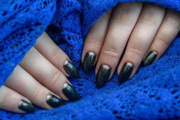 Beautiful winter manicure. Black lacquer with luster and white patterns of snow and frost. The blue background is also with beautiful curled drawings
