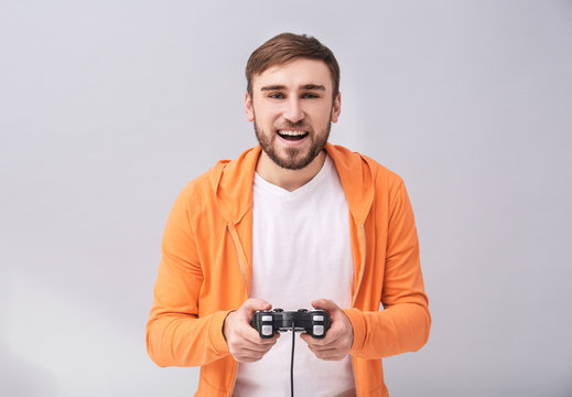 Happy man with video game controller on grey background