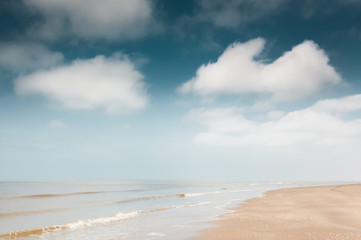 Sandy beach and blue sky with clouds. Coast of the North sea in the Netherlands