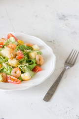 Caesar salad with shrimps on a white background