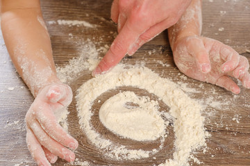 Fototapeta premium Close up of children's and mother's hands kneading dough. Child prepares burritos or burrito