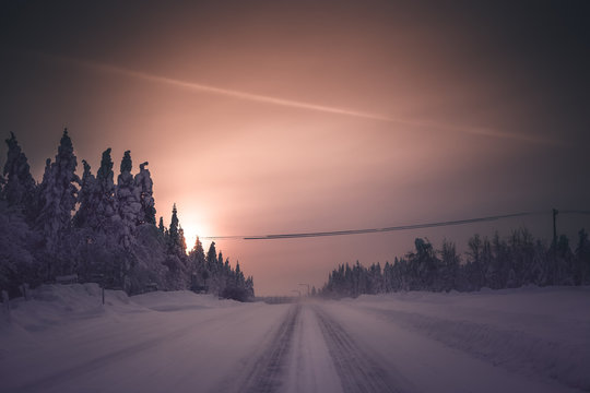 Snowy Winter Road And Hazy Sunset. Finland