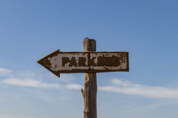 Parking faded arrow sign on wooden post