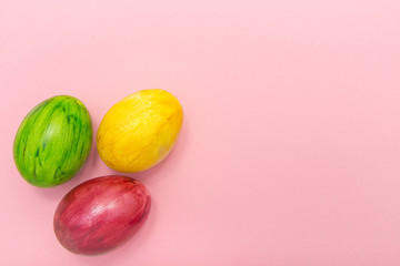 Easter Eggs on pink background.Yellow green and maroon eggs handmade new style of colouring form flower on a colored cardboard. Pattern, easter concept, trendy colors