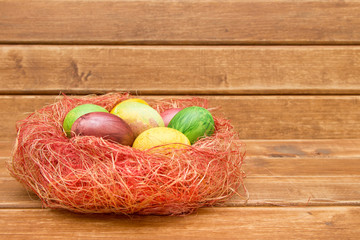 Colorful easter eggs in nest  on wooden background. Eggs handmade new style of colouring . Pattern, easter concept.