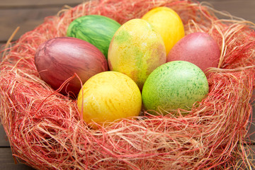 Fototapeta na wymiar Colorful easter eggs in nest on wooden background. Eggs handmade new style of colouring . Pattern, easter concept.