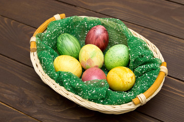 Colorful easter eggs in basket on wooden background. Eggs handmade new style of colouring . Pattern, easter concept.