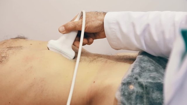 Male doctor taking a sonogram of male patients abdomen in the clinic