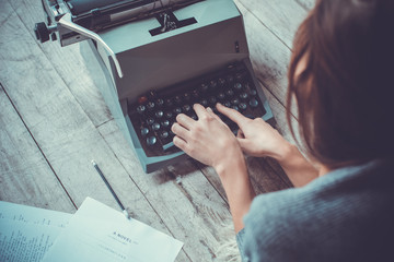 Young woman writer in library at home creative occupation typing typewriter