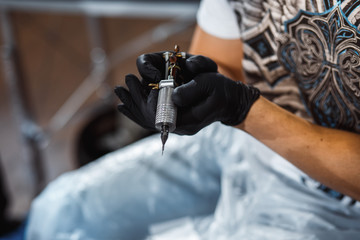 master tattooist makes a tattoo on the skin of the client with special equipment