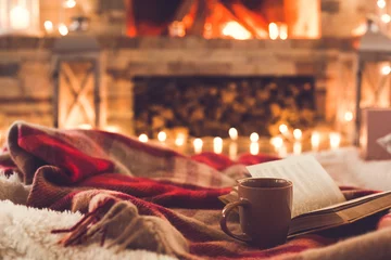 Fototapeten One cup and a book near the fireplace winter concept © Viktoriia