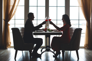 Fototapeta na wymiar Young couple having romantic dinner in the restaurant toast