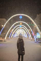 Women walking under lighting arch during the snowfall