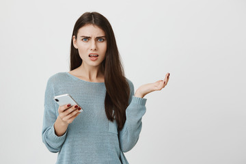 Shot of clueless young caucasian brunette woman looking at camera with confused and puzzled...