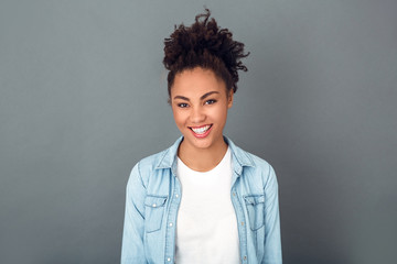 Young african woman isolated on grey wall studio casual daily lifestyle smiling