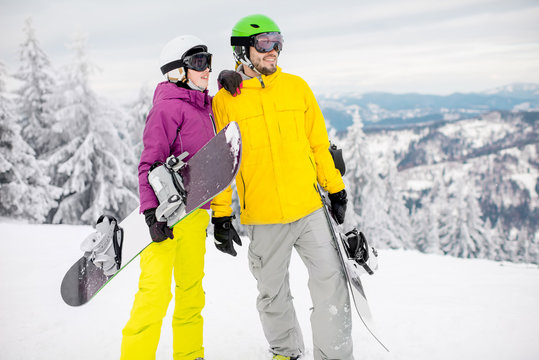 Young couple walking with snowboards during the winter vacation on the snowy mountains