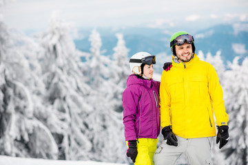 Fototapeta na wymiar Young couple standing in winter sports clothes during the winter vacation on the snowy mountains
