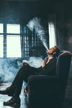 Man gets pleasure from vaping. Healthy alternative to nicotine cigarettes. Exhaling lots of fumes and feeling relaxed and satisfied.