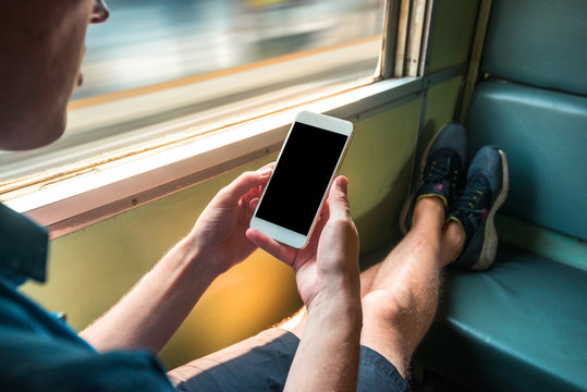 Man sitting in a train in motion holding a phone in his hands