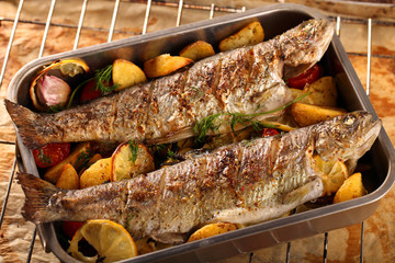 grilled fish with potatoes on wooden background