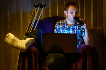A man with a broken leg is spending time with a laptop.