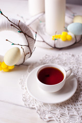 Easter breakfast - light decor, wreaths, candles and a cup of tea on a white wooden background