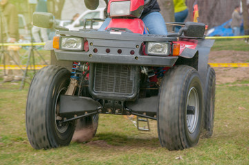 Obraz premium Mensch fährt ein Quad dynamisch in voller Fahrt auf Grasfläche im Sonnenschein