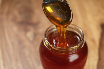 organic honey drips from spoon in jar