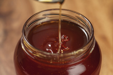 organic honey drips from spoon in jar