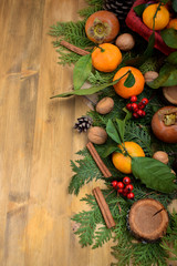 Winter composition consisting of thuja branches, berries, persimmon, mandarins, nuts and cinnamon sticks. Copy space