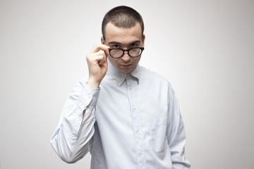 Young handsome man in blue shirt looking through his glasses. Doctor or businessman or professor style concept. Selective focus and shallow DOF