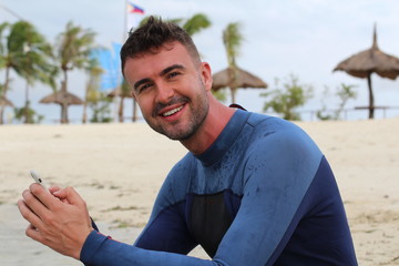 Handsome man texting from the beach 