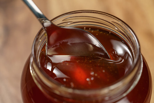 organic honey drips from spoon in jar