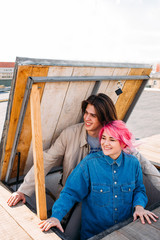 Hipster couple on the roof. Happy pink hair girl and smiling long haired boy. Teenage friendly or romantic relationship. Exciting pastime